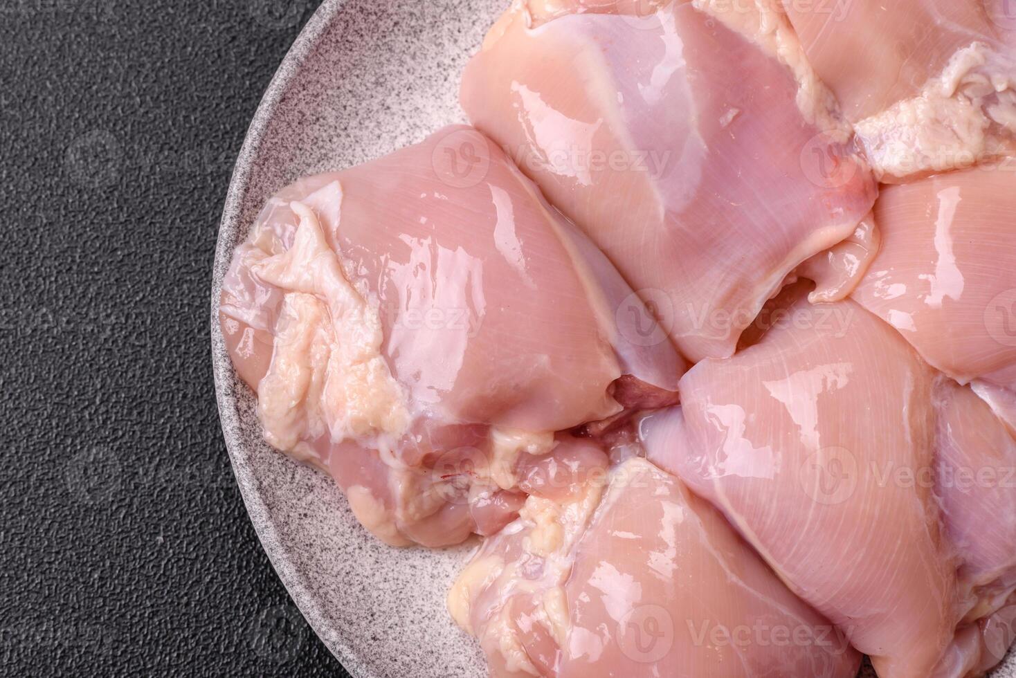 Fresh raw chicken thigh fillets with salt, spices and herbs photo
