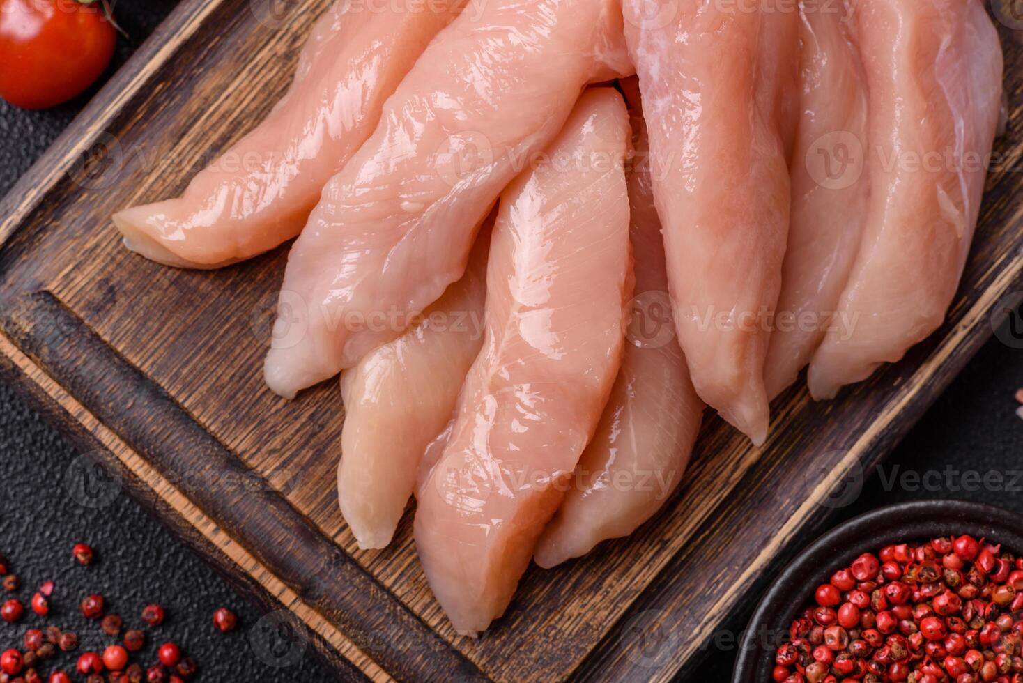 Raw chicken fillet cut into strips with spices and herbs photo