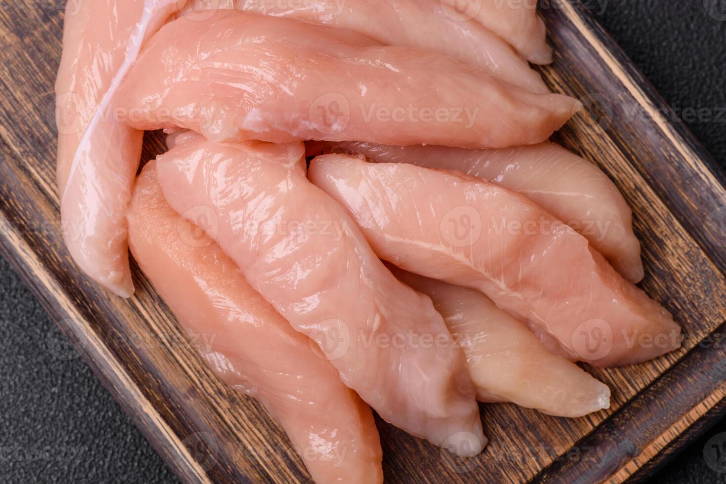 Raw chicken fillet cut into strips with spices and herbs photo