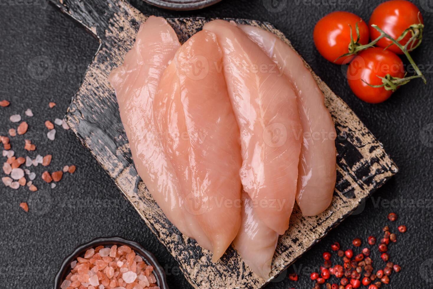 Raw chicken fillet cut into strips with spices and herbs photo