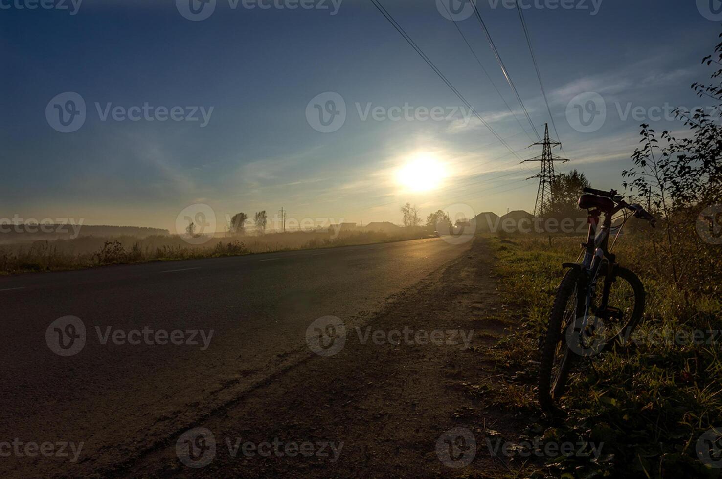 Sunset in background of the road and fields with grass and trees. photo