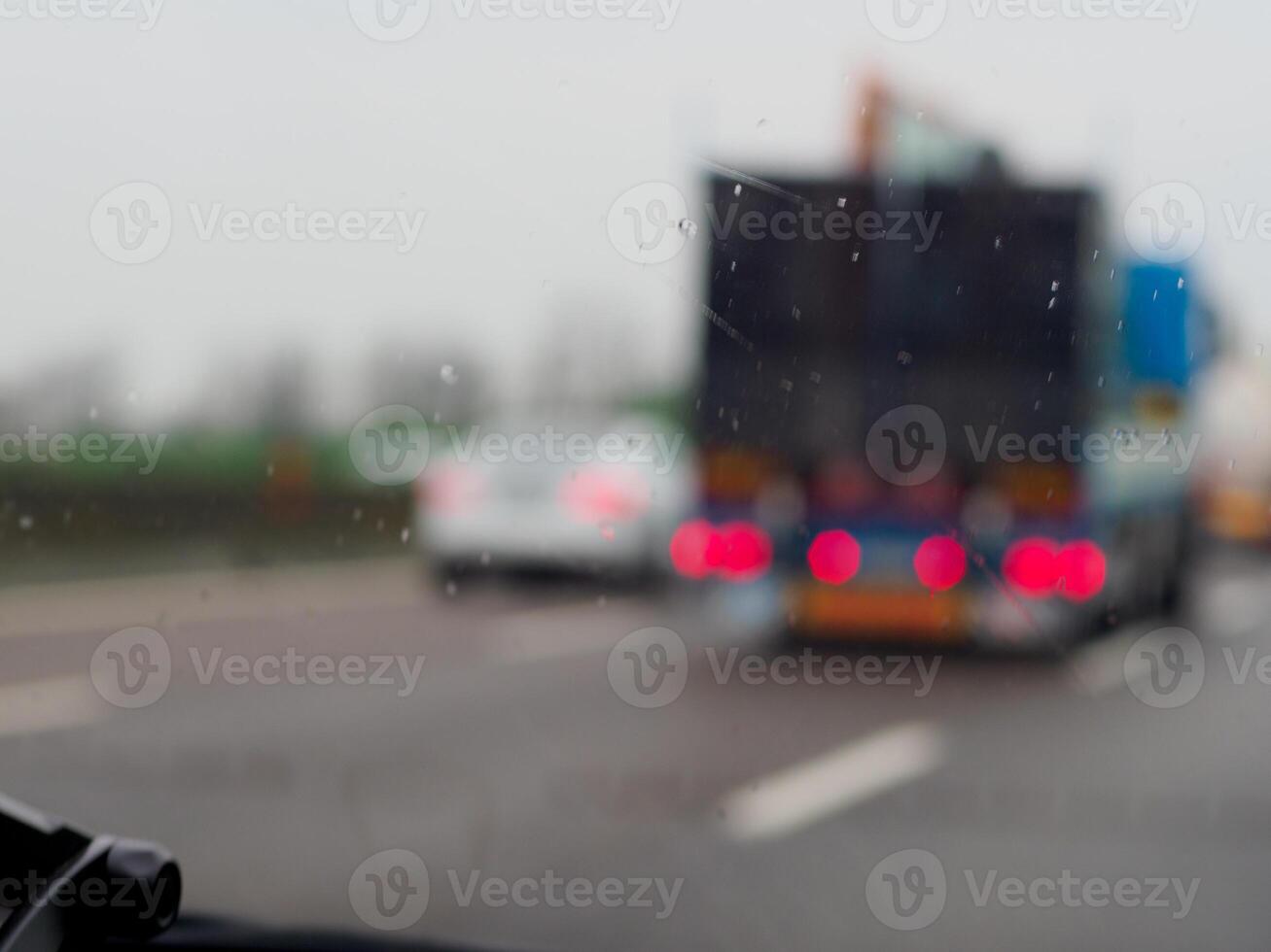 A blurry image of a busy expressway with cars and a truck under a storm rainy day photo