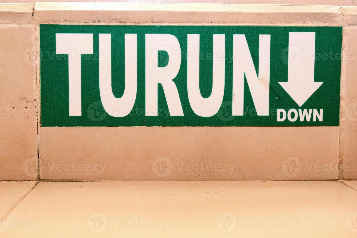 Green Turn Down Directional Sign on Beige Wall photo