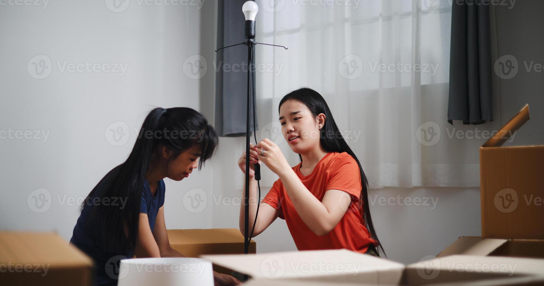 Portrait of Two Asian women are helping to assemble a floor lamp in the living room in new home. Moving to a new home concept photo