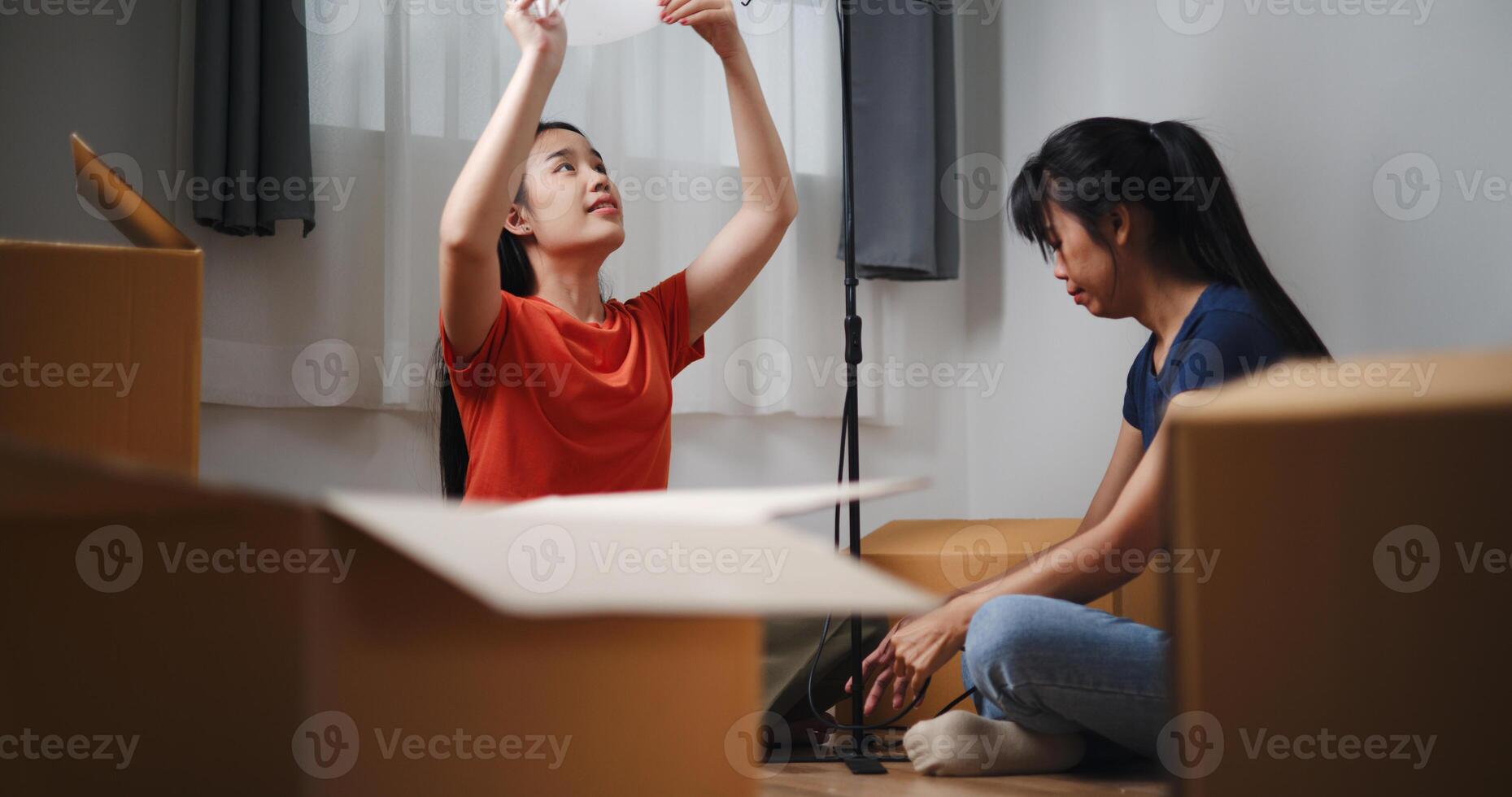 Portrait of Two Asian women are helping to assemble a floor lamp in the living room in new home. Moving to a new home concept photo