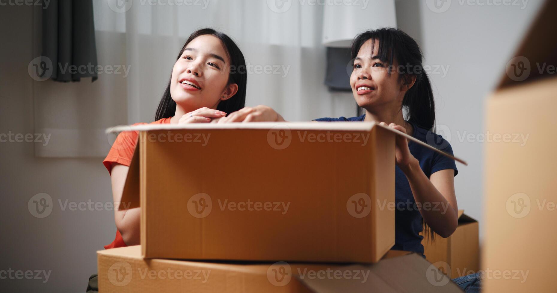 Portrait of Two siblings happily sit on the floor talking as they unpack belongings from boxes to decorate a room in new home. Moving to a new home concept photo