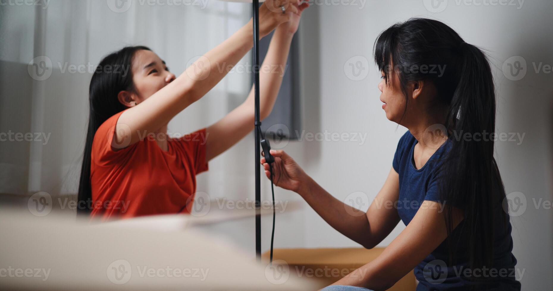 Portrait of Two Asian women are helping to assemble a floor lamp in the living room in new home. Moving to a new home concept photo