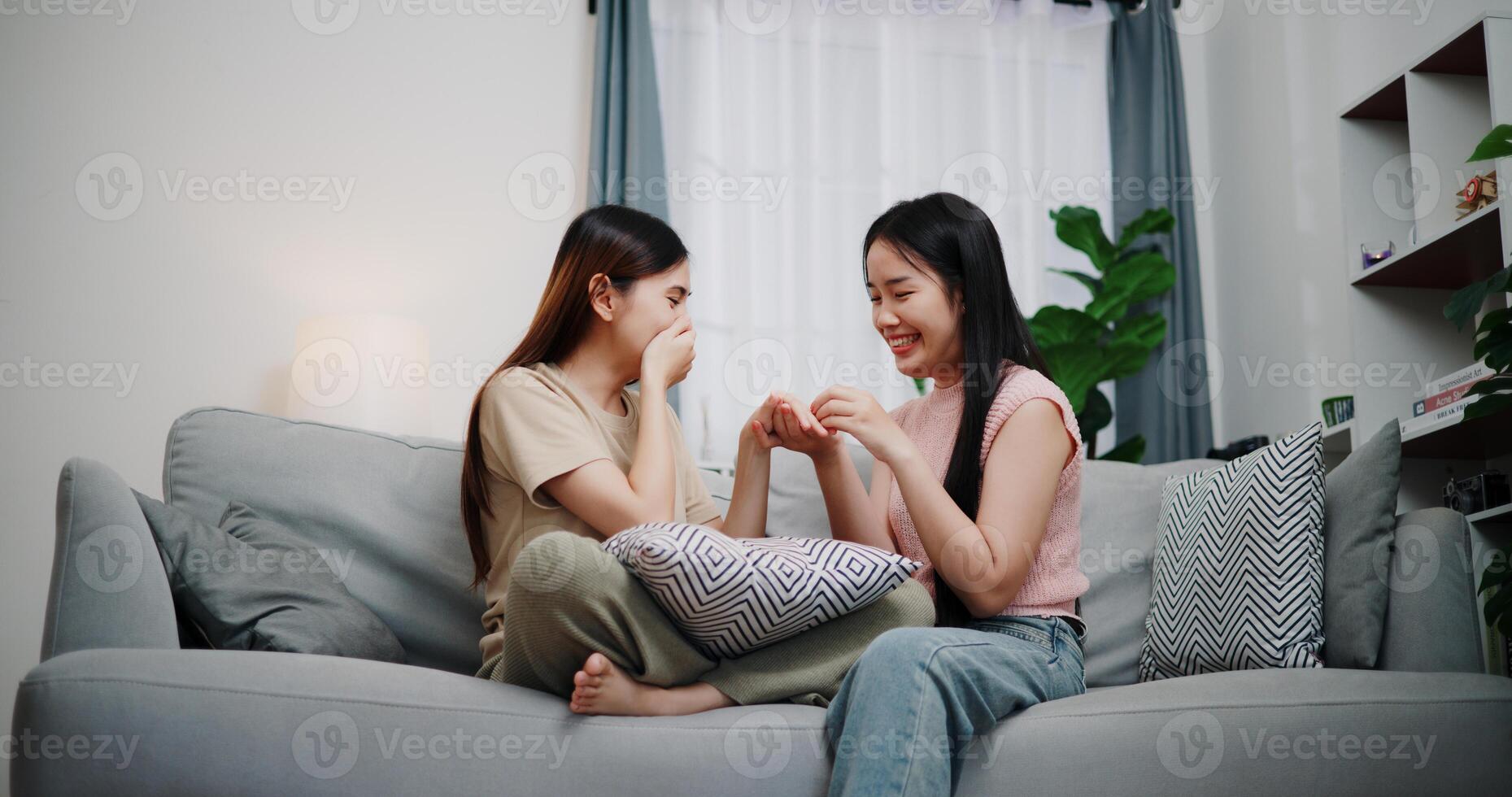 Low angle view, Asian lesbian surprises girlfriend with proposal with wedding ring and smiles happily during romantic moment in living room at home. Asian LGBTQ couple. photo