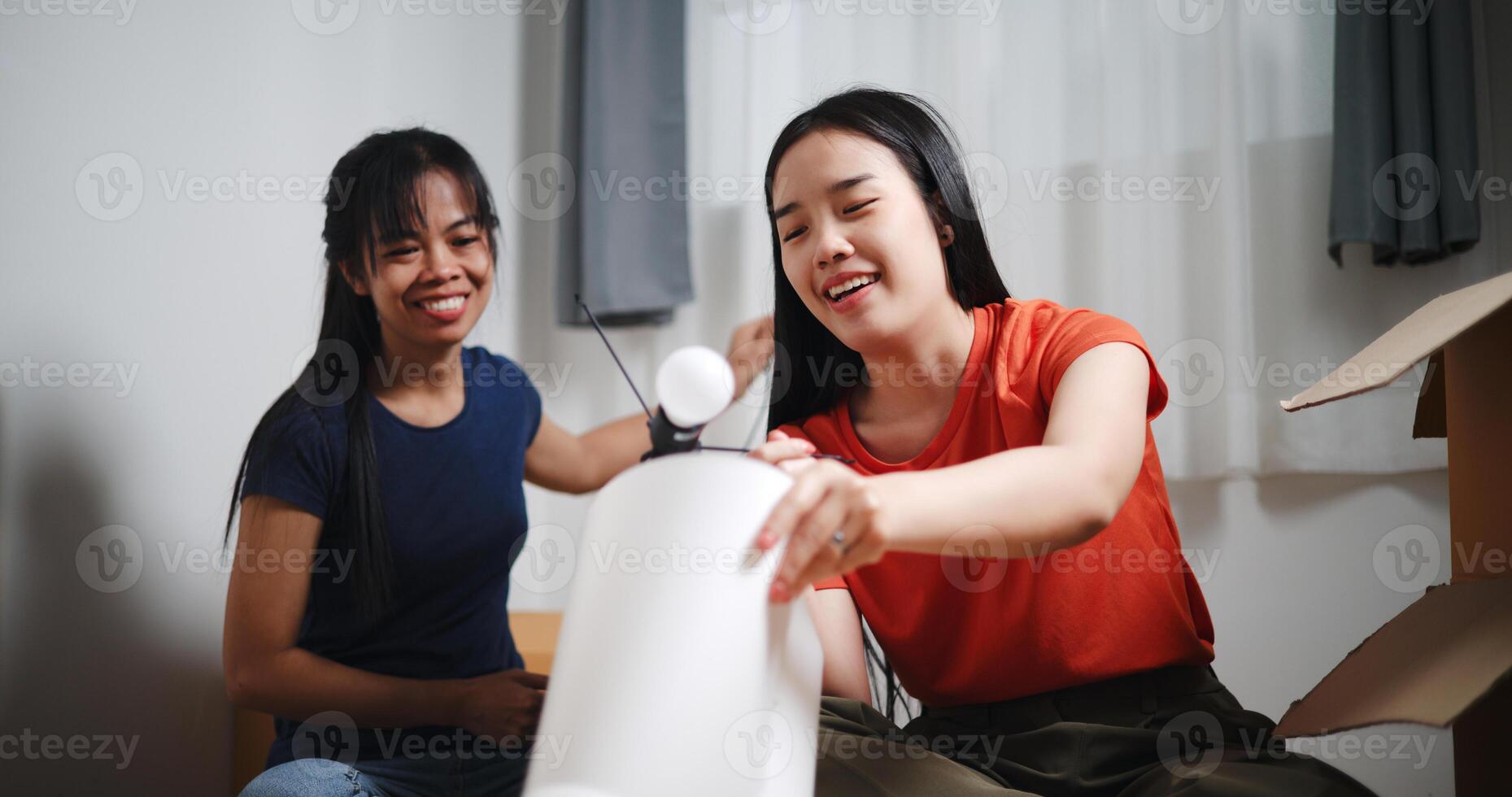 Portrait of Two Asian women are helping to assemble a floor lamp in the living room in new home. Moving to a new home concept photo