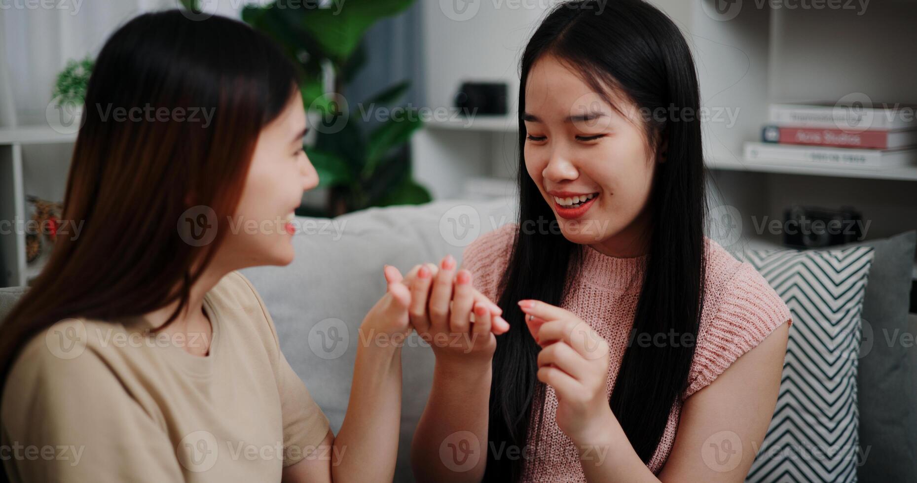 Asian woman proposes to girlfriend and surprises her with wedding ring on sofa at home photo
