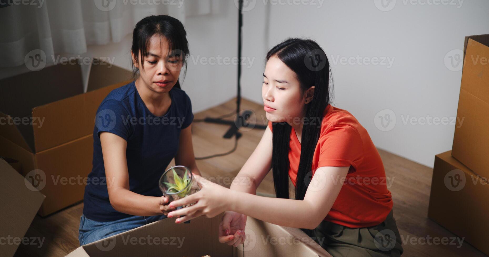 High angle view, Two siblings happily sit on the floor talking as they unpack belongings from boxes to decorate a room in new home. Moving to a new home concept photo