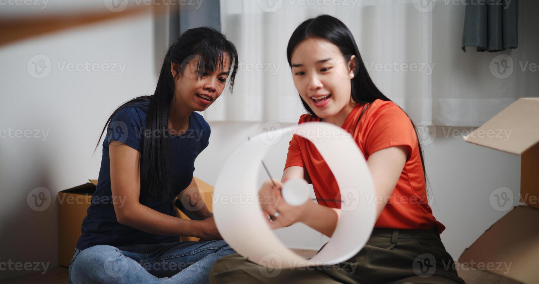 Portrait of Two Asian women are helping to assemble a floor lamp in the living room in new home. Moving to a new home concept photo
