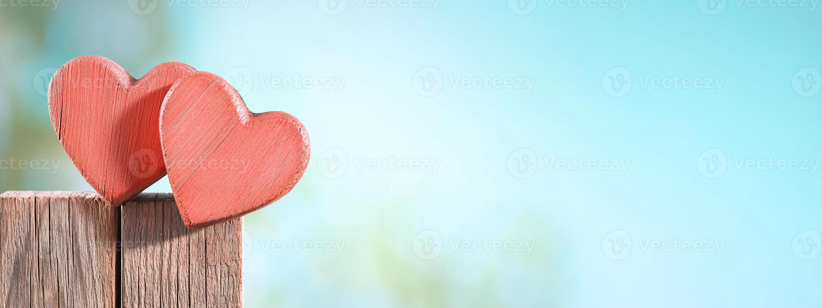 Two wooden hearts on a rustic surface against a soft blue background. photo