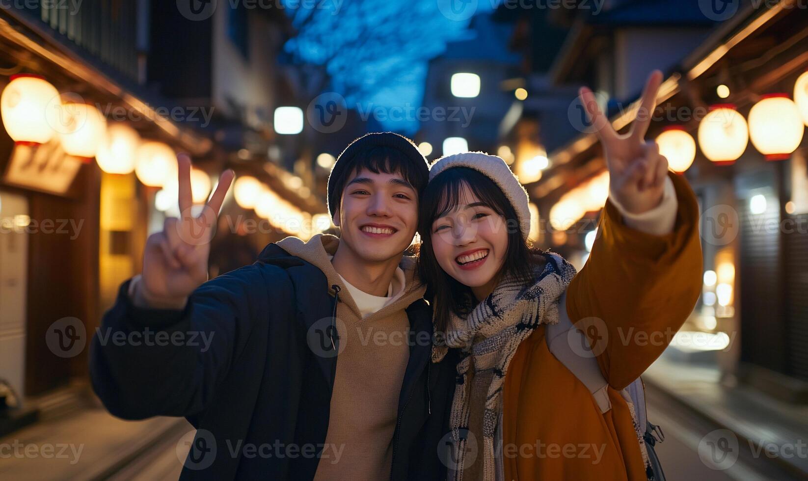 A cheerful couple posing with peace signs in a festive street at dusk. photo