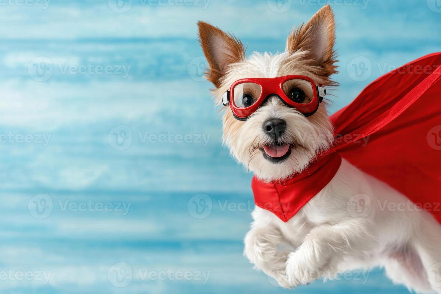 Comical superhero dog in red cape and goggles striking a playful pose against a blue background photo