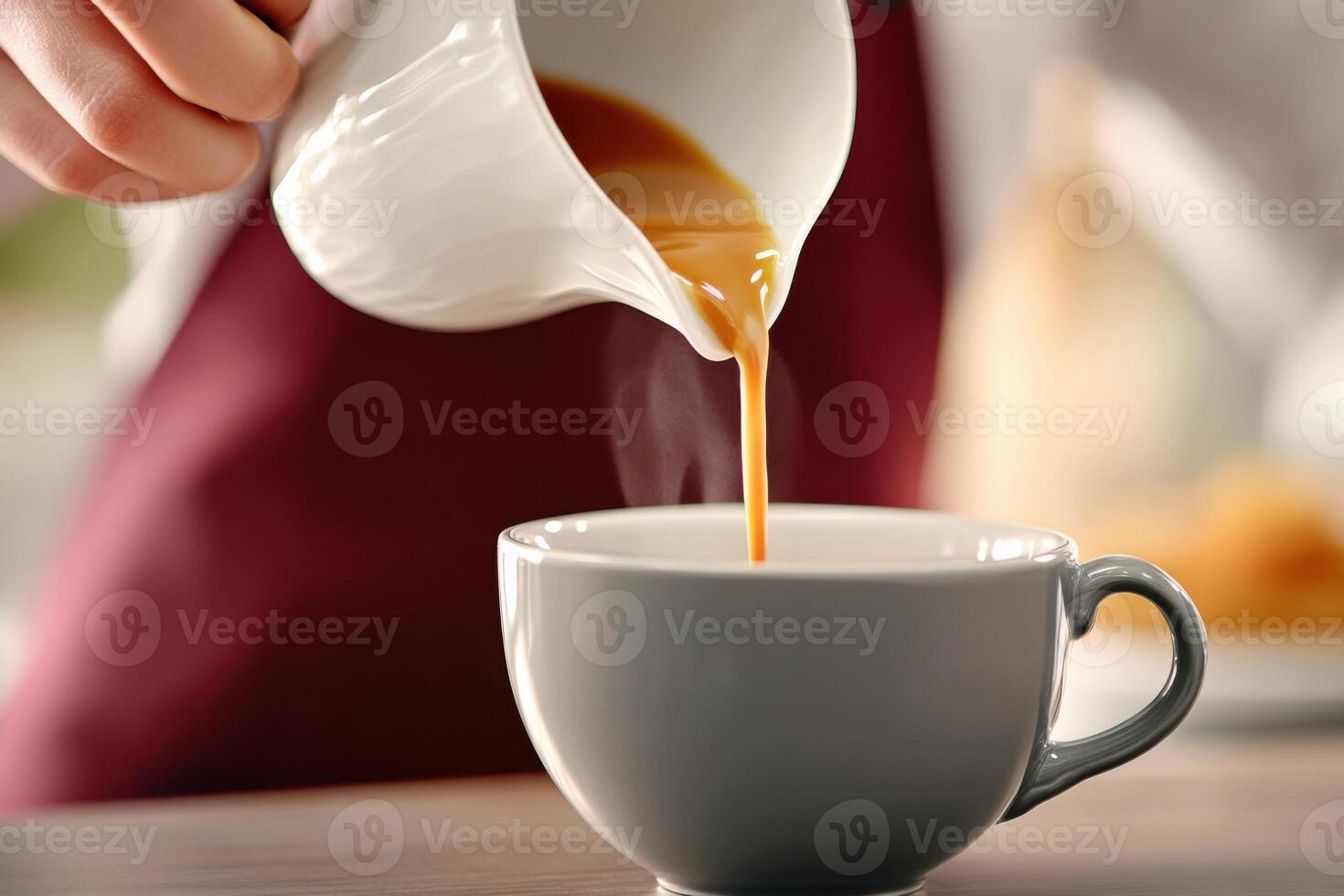 Barista pours freshly brewed coffee into a gray ceramic cup on a wooden counter during a cozy cafe moment photo