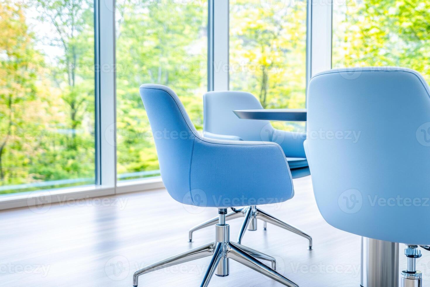 Corporate meeting room with navy conference table and light blue chairs bathed in natural light from large windows overlooking greenery photo