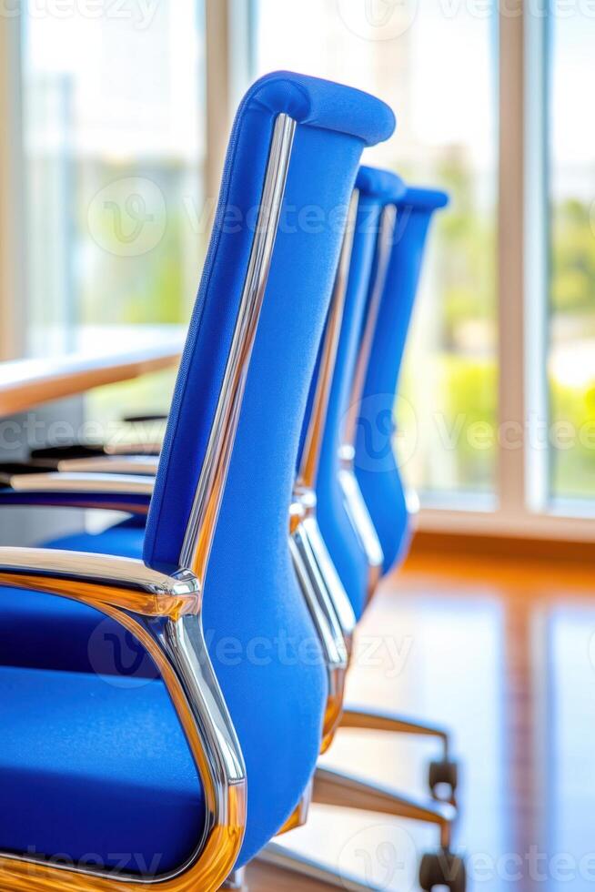 Corporate meeting room featuring a navy conference table surrounded by light blue chairs illuminated by natural light through large windows photo