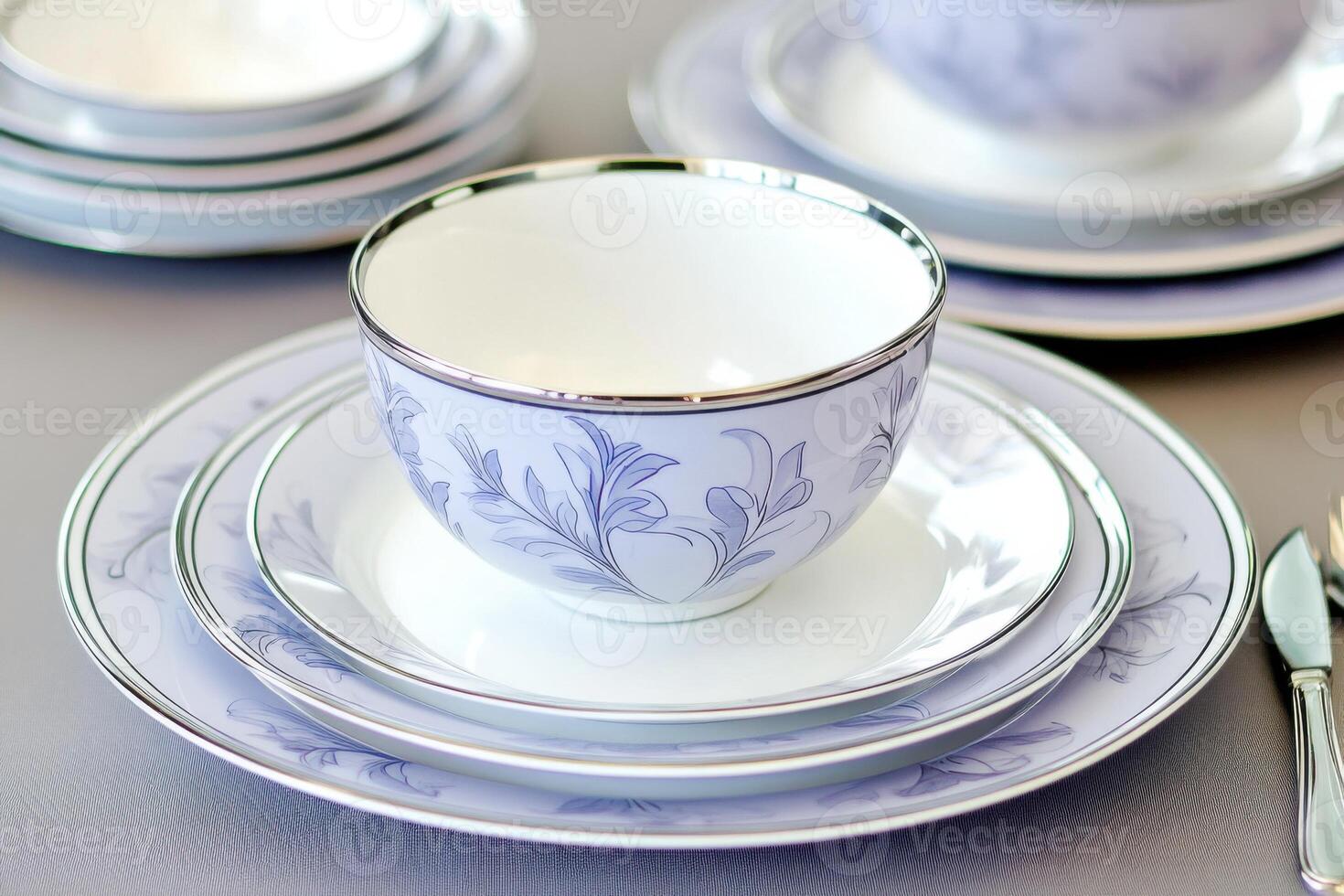 Elegant porcelain dishes set in light lilac with silver accents arranged on a taupe tablecloth for a sophisticated dining experience photo