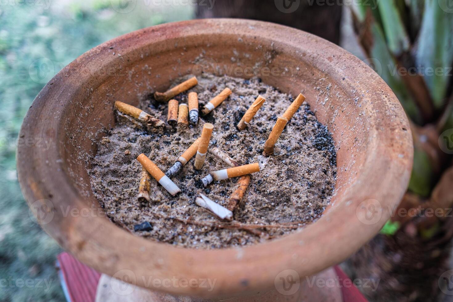 Cigarette ash butts in ashtray with sand on container tray photo