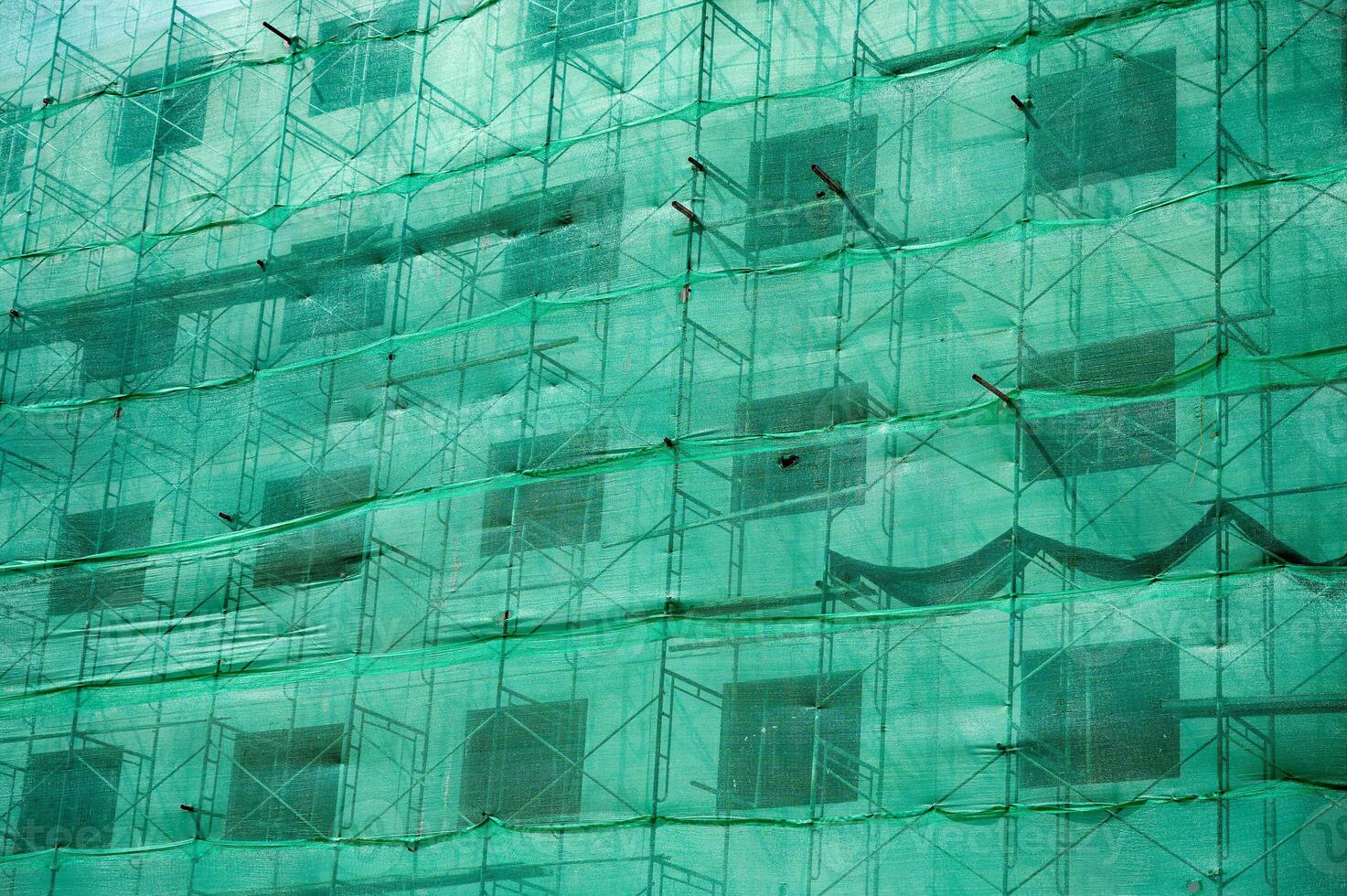 Building structure with green netting shade and scaffolding photo