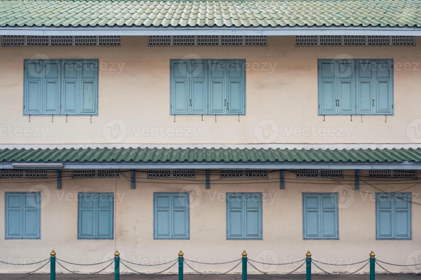 Retro building with green tile roof, traditional windows and fence photo