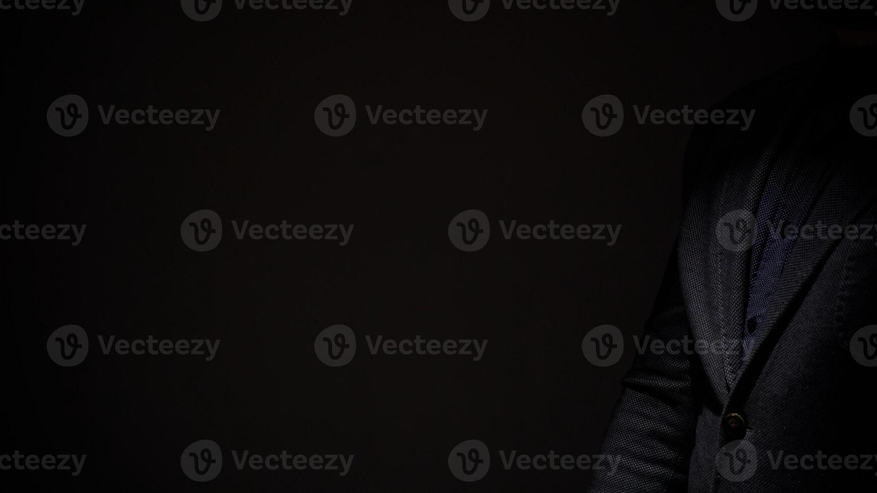 A man in a suit is standing in the dark photo