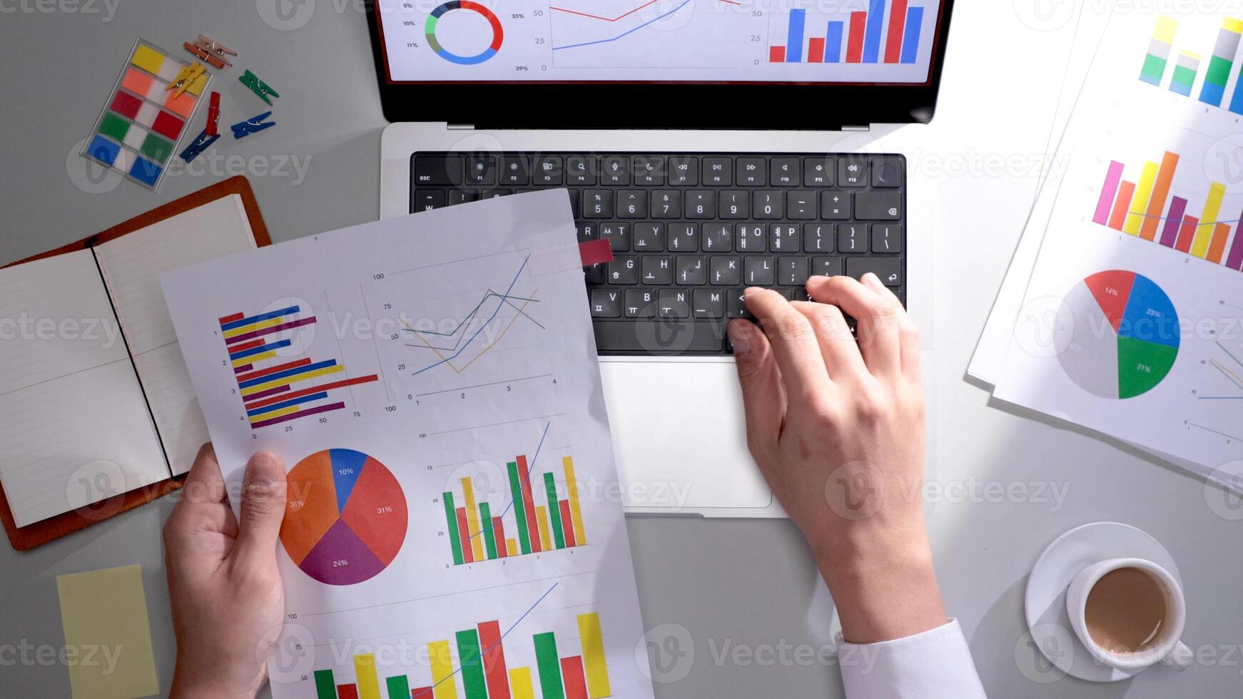 A person is using a laptop with graphs and papers photo