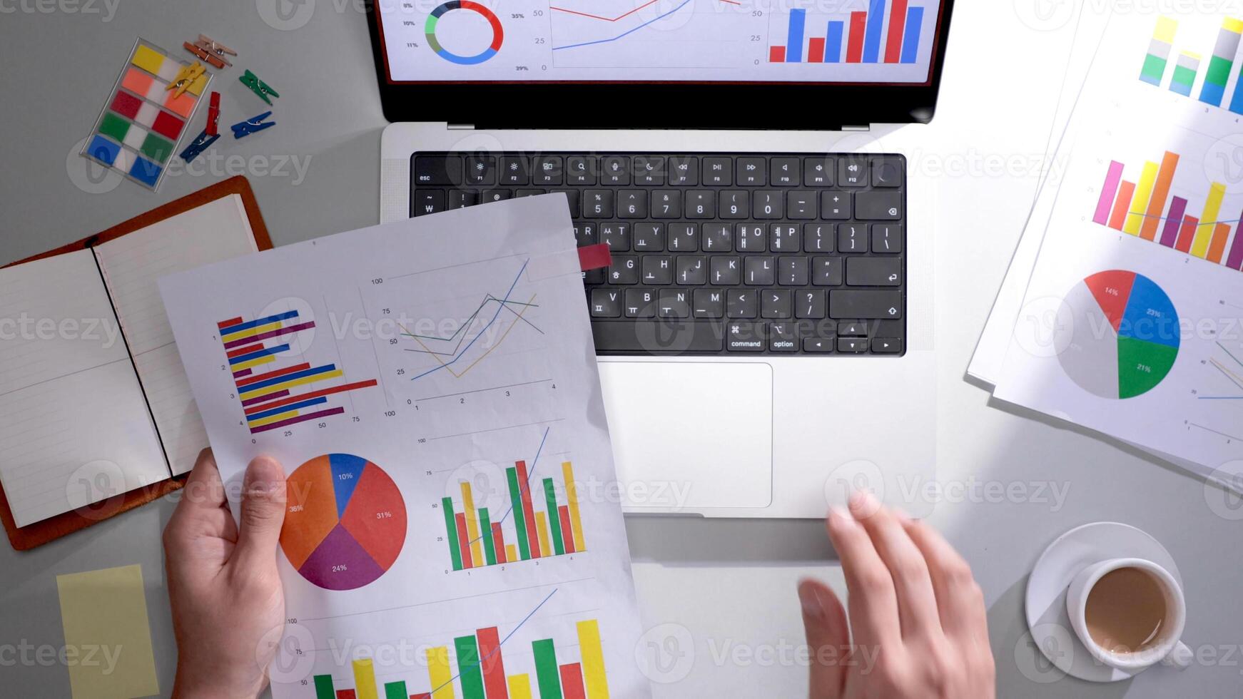 A person is using a laptop with graphs and papers photo