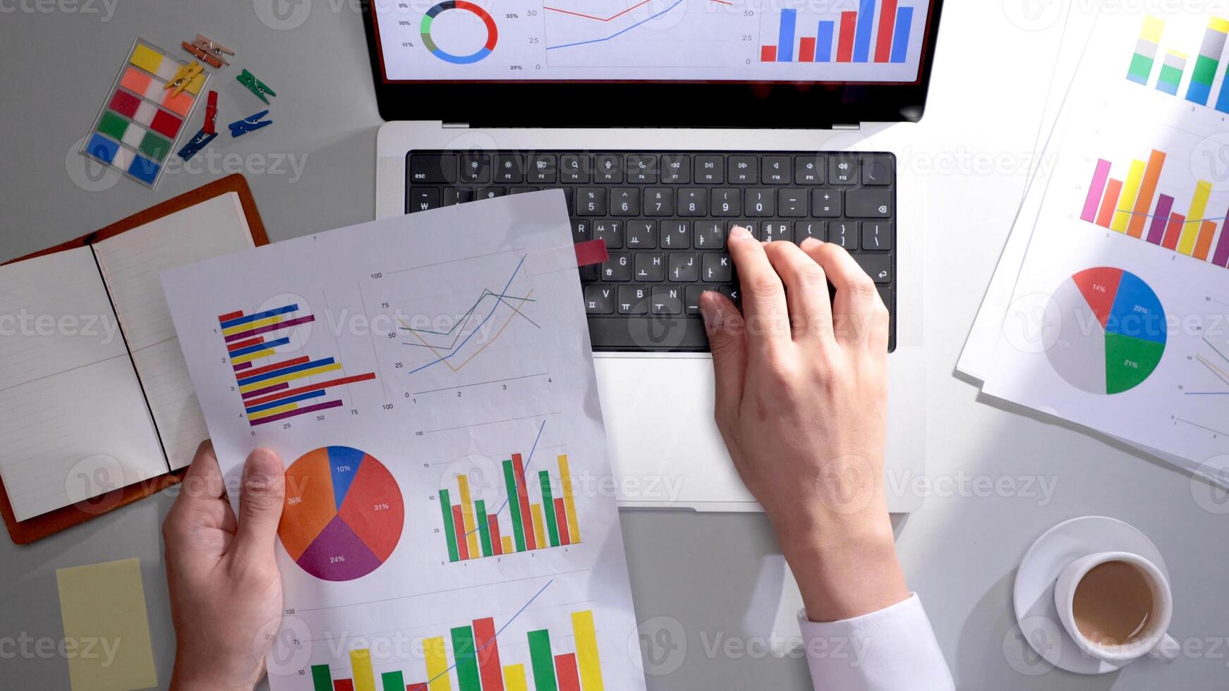 A person is using a laptop with graphs and papers photo