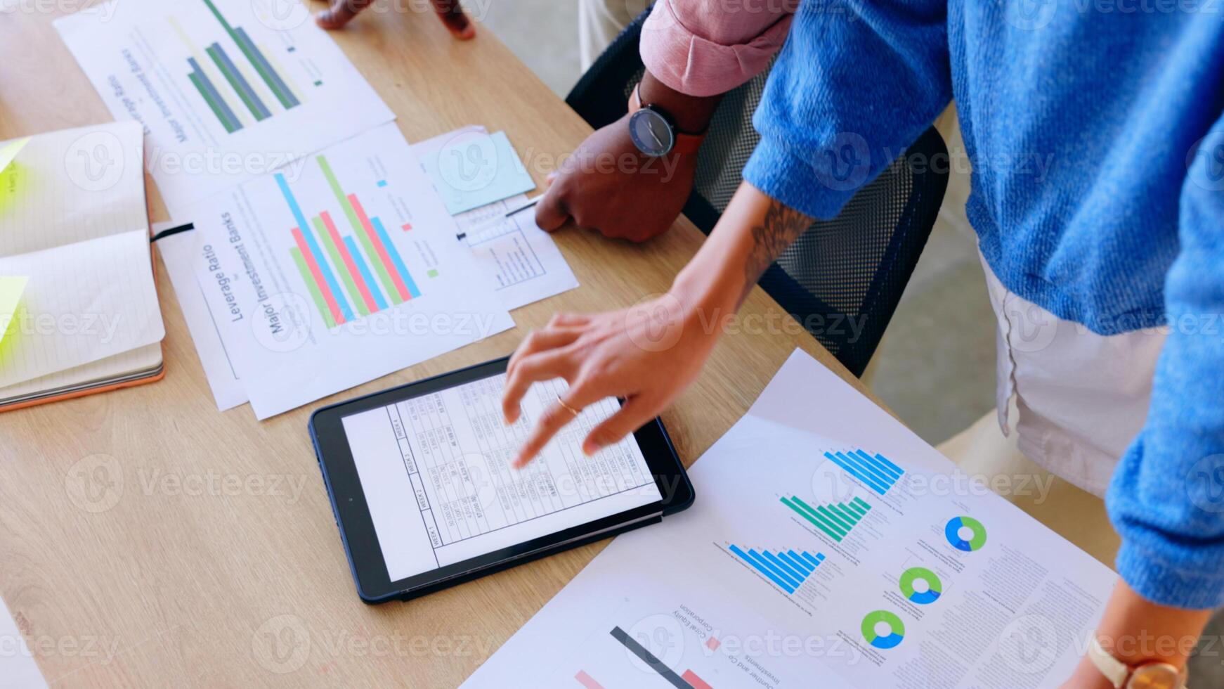 Business people working on a tablet with graphs and papers photo