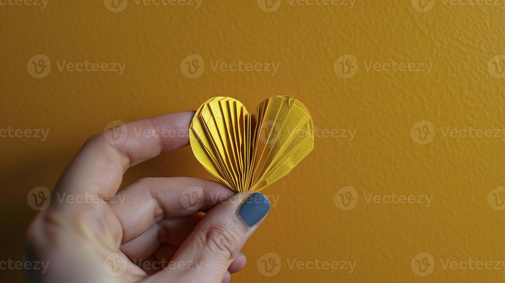 Hand with blue nails holds folded yellow origami heart image copy space. Symbolic gesture, artistic creativity banner background. Heartfelt moment concept photography copyspace photo