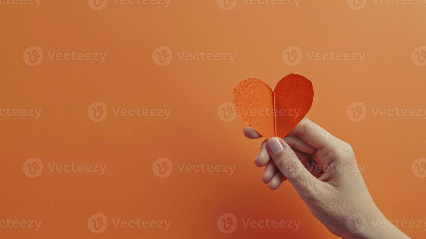 Female hand delicately holding folded orange paper heart image copy space. Artistic creation, heartfelt banner background. Creativity, warmth and affection concept photography copyspace photo