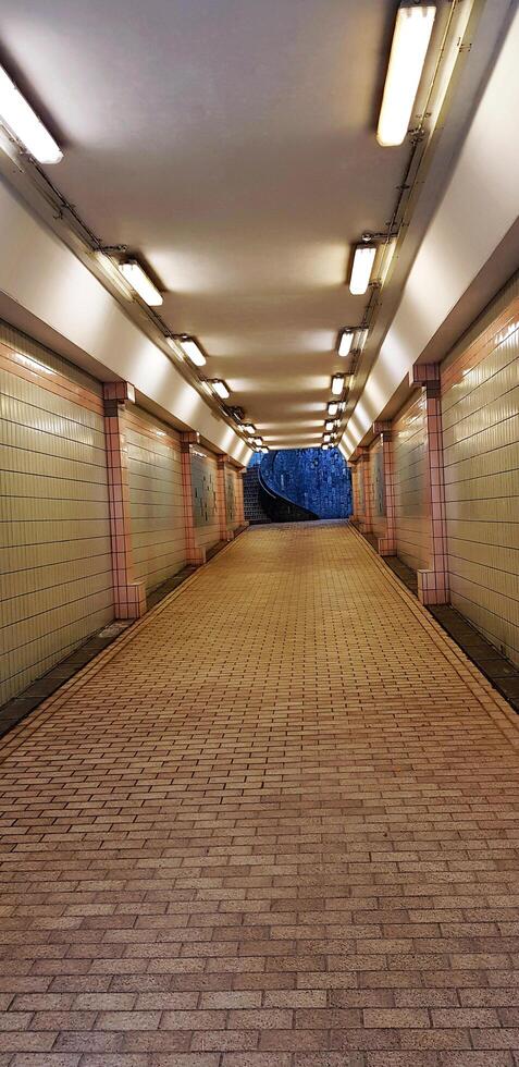 Long straight walkway in a tunnel with lights in Singapore. Exterior design and way to destination concept. photo
