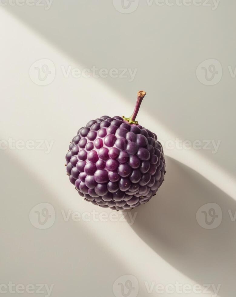A purple fruit is sitting on a white surface photo