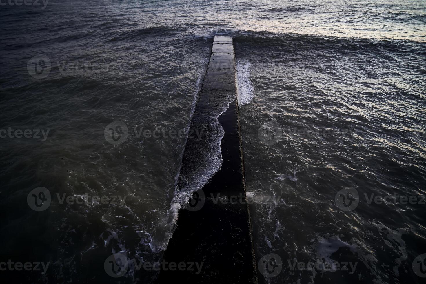Landscape with a stone pier and raging waves in the sea. photo