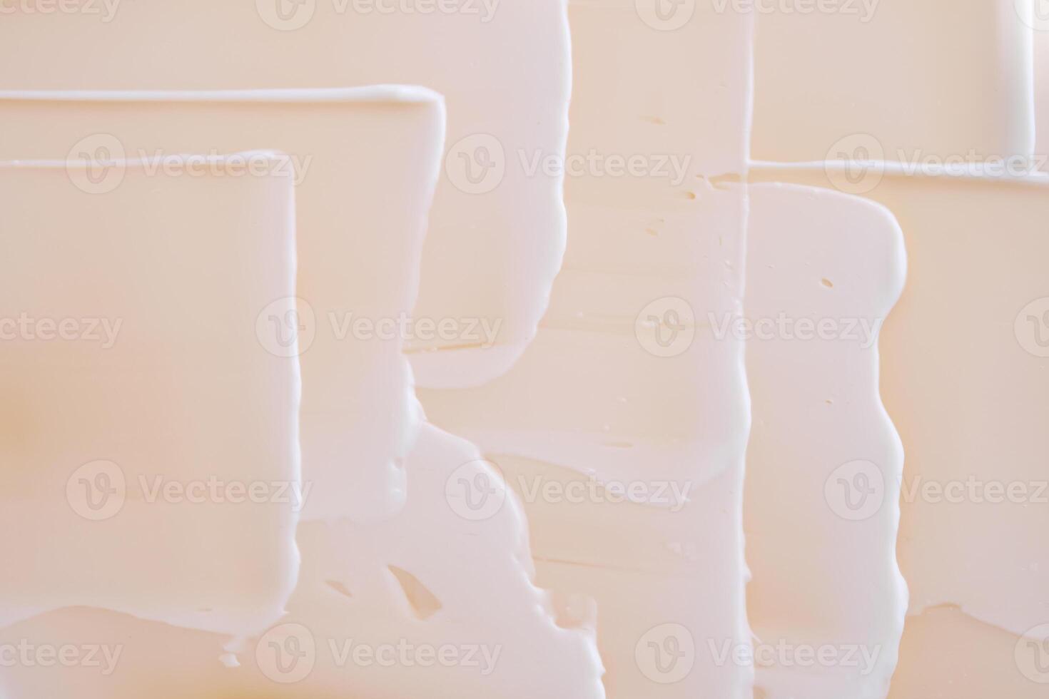 Swatch with white cream texture on a beige background. photo