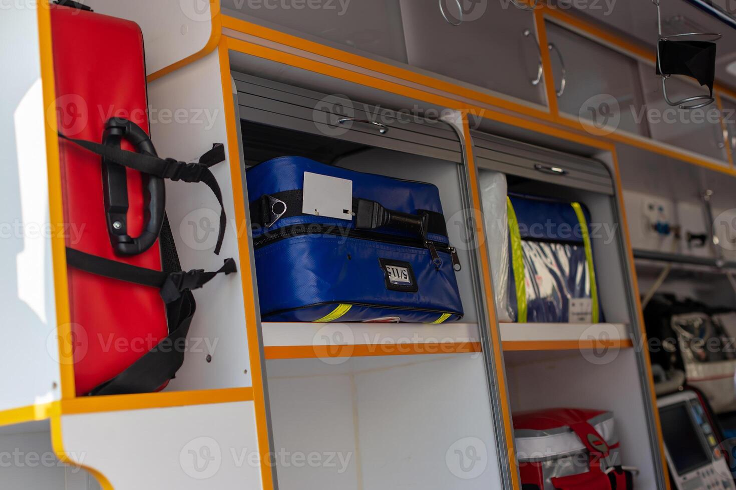 Inside the ambulance, medical supplies and storage compartments are visible, with red and blue bags photo