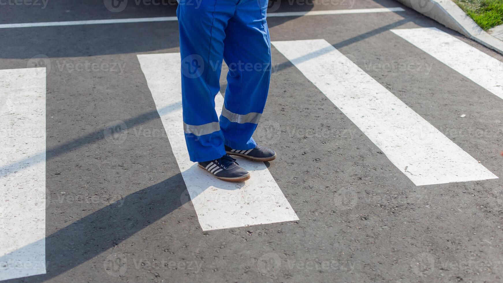 Partial view of a paramedic in uniform standing on a zebra crossing, focus on feet photo