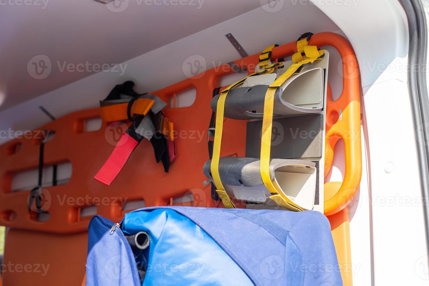A close-up of an orange stretcher with a fixation hanging on the wall in the cabin of an ambulance photo