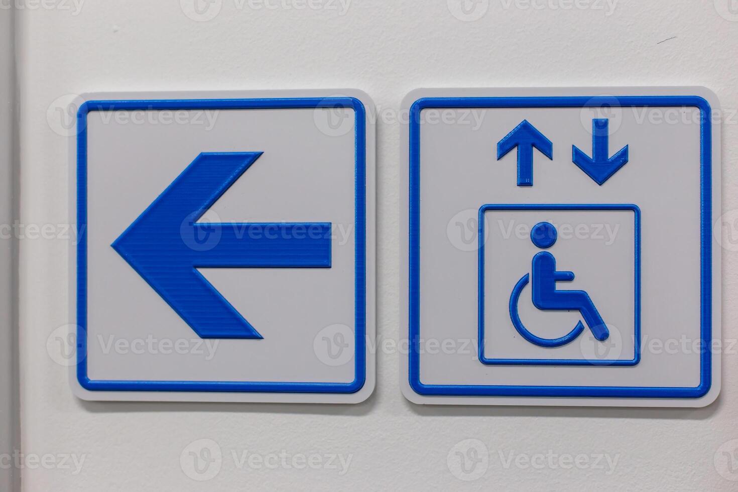 A blue arrow and elevator access signs disabled person on the wall photo