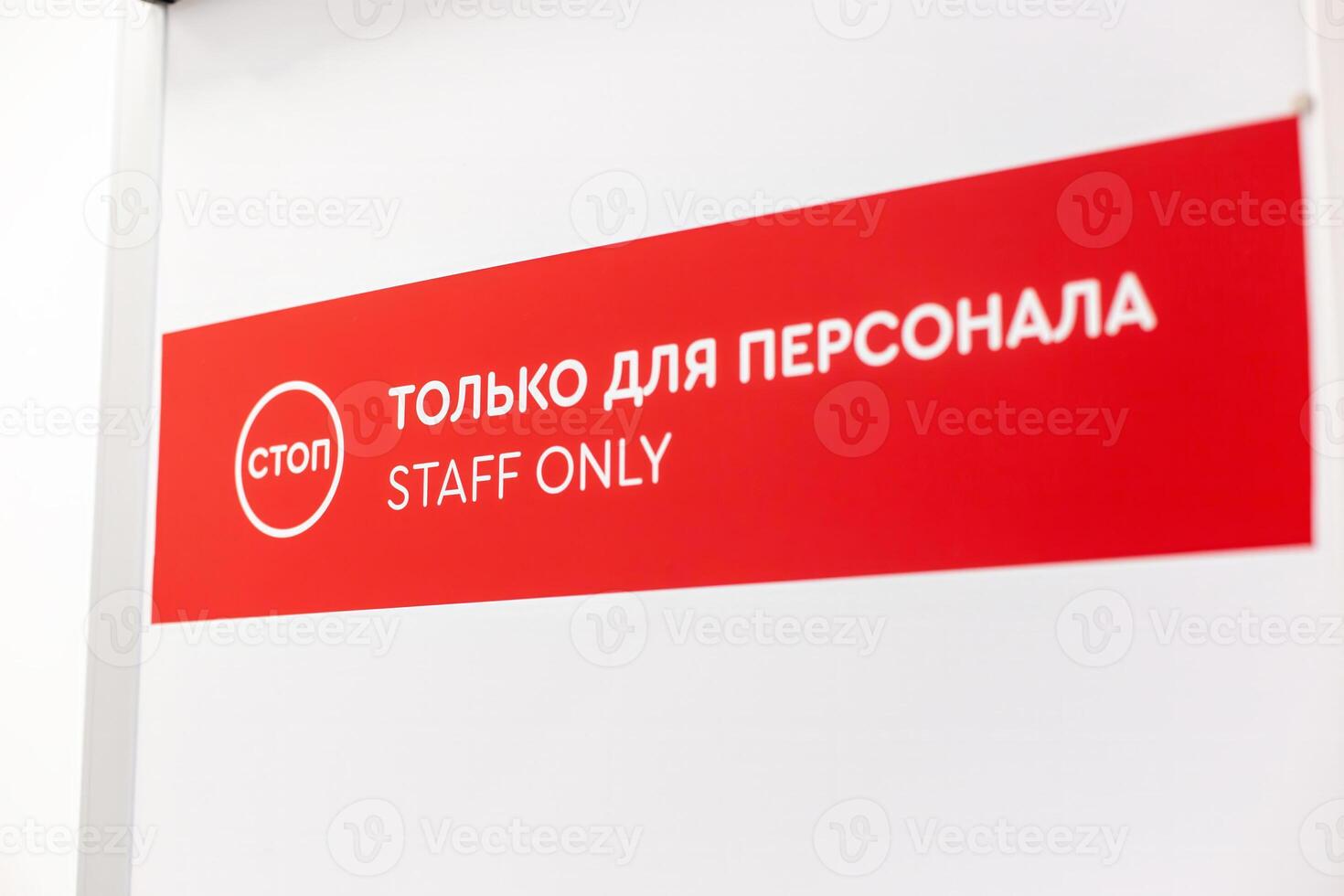 Red and white 'Staff Only' sign with bilingual text in English and Russian above door photo