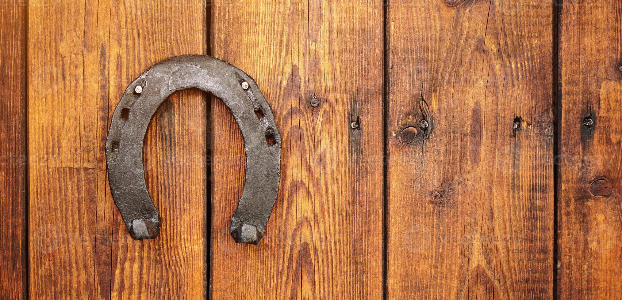Front view of a wooden door with an iron lucky horseshoe for good luck. Concept for luck and fortune. A talisman superstition for luck. photo