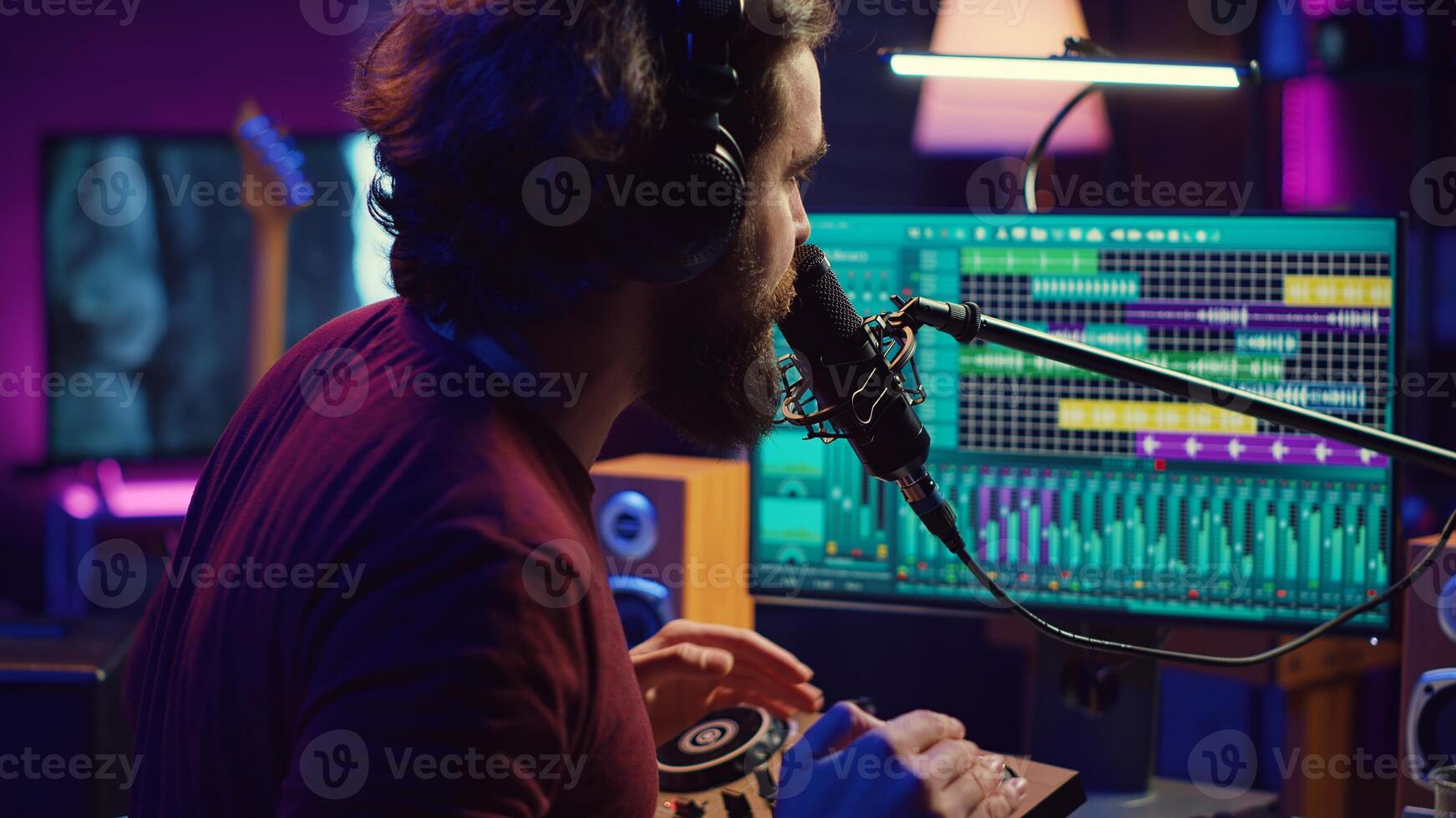 Music producer singing at home studio microphone to record songs, editing and adjusting volume levels in post production. Audio engineer conducts recordings of vocals, mixing console. Camera A. photo