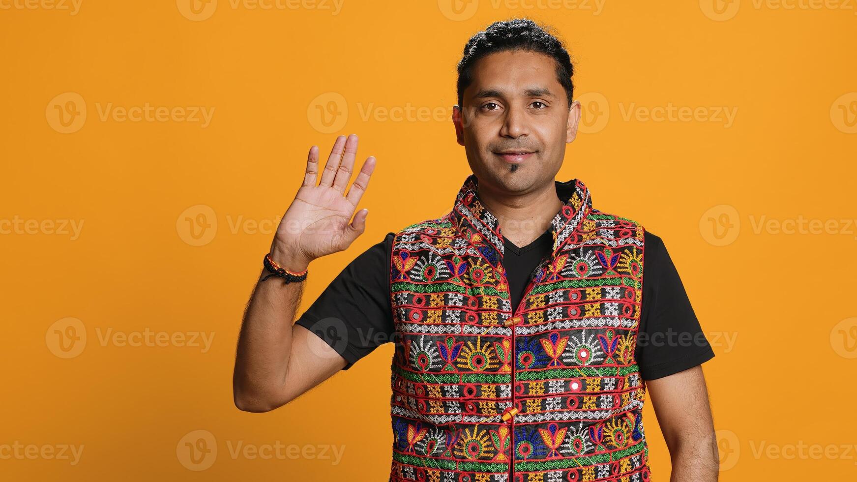 Portrait of jolly indian man with colorful garment smiling, looking pleased, isolated over studio background. Joyous person in traditional attire feeling carefree, camera A photo
