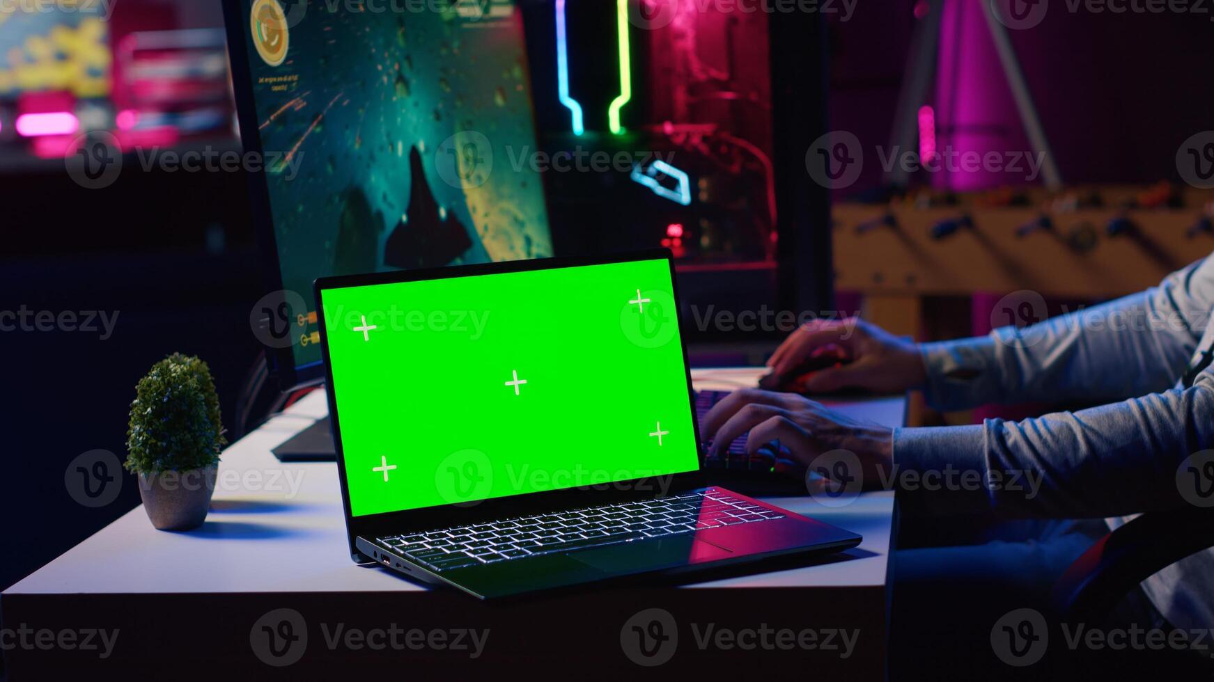 Green screen laptop next to man playing with friends online, shooting asteroids together in spaceship flying game. Mockup notebook and gamer cooperating with teammates in coop videogame photo