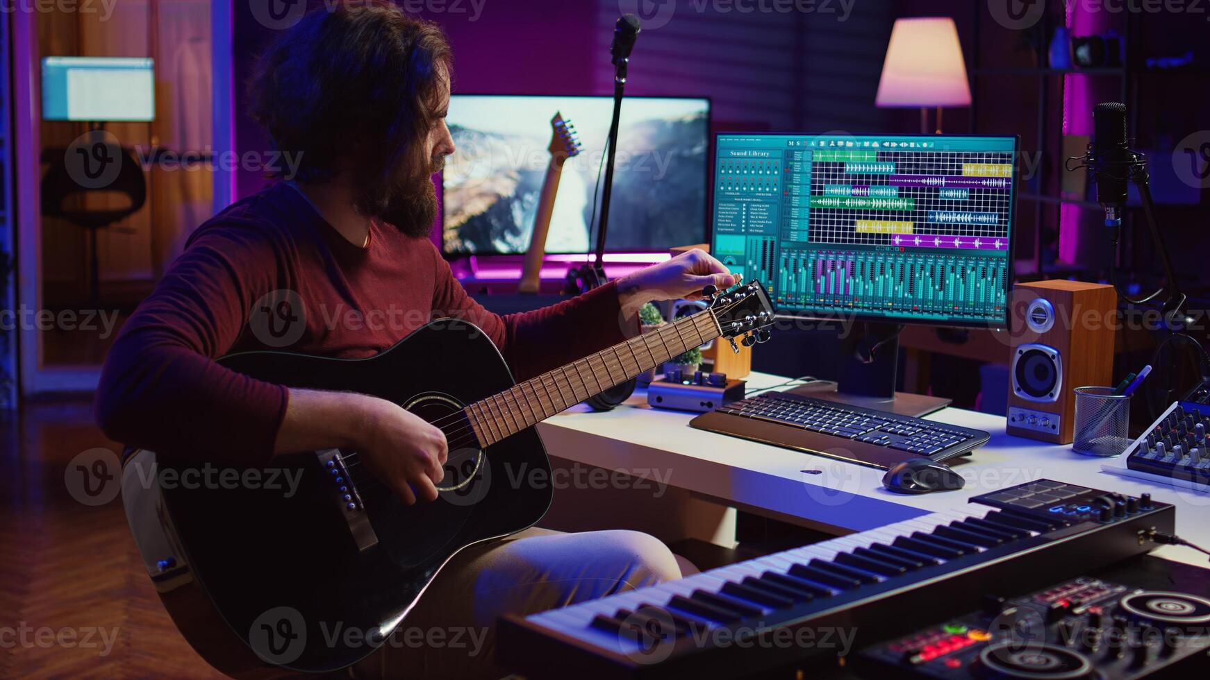 Musician trying to tune the sound of his guitar in home studio, adjusting knobs before playing tunes and recording on daw software. Advanced mixing and mastering techniques. Camera B. photo