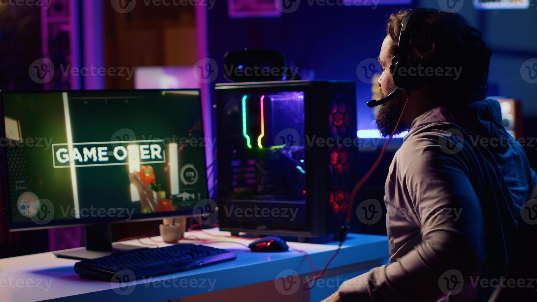 Gamer throwing headphones in frustration after receiving game over screen in first person shooter. Player upset after being defeated in videogame, losing all health, failing to win level photo