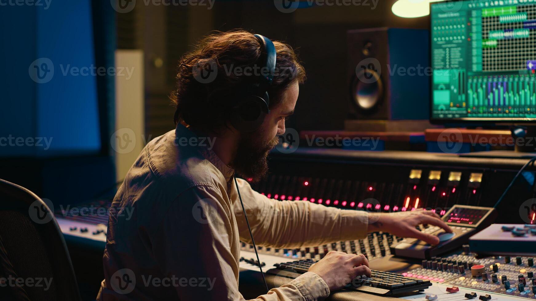 Audio expert operating motorized faders and mixing console in control room, using sliders and switchers buttons to edit and process sounds. Music designer and producer recording tracks. Camera A. photo