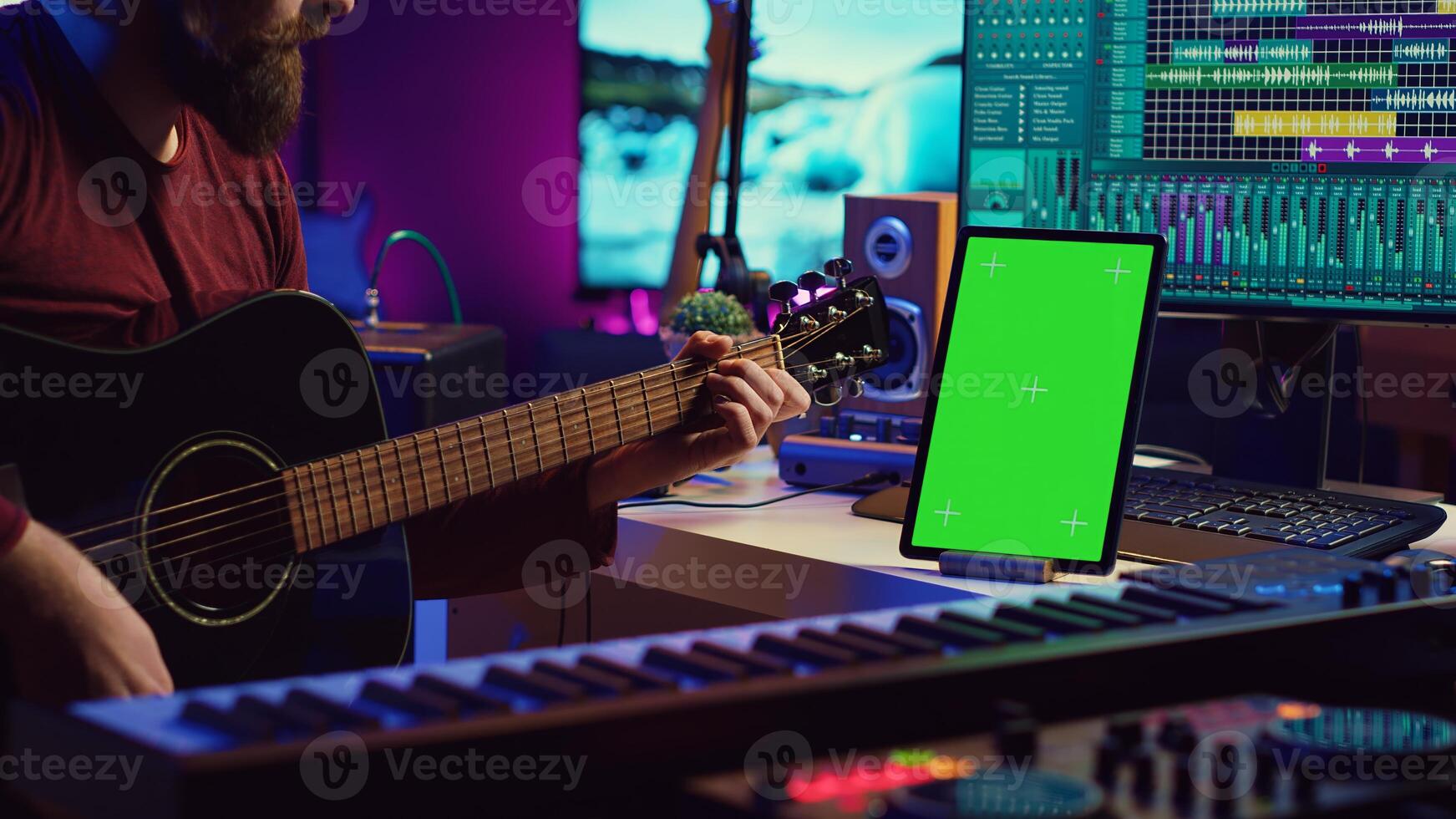 Male artist learning to play guitar on online lesson tutorial, practicing acoustic instrument and looking at phone with greenscreen display. Music producer doing rehearsal guitar play. Camera A. photo